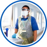 a male healthcare professional wearing PPE and pushing a trolley in a corridor