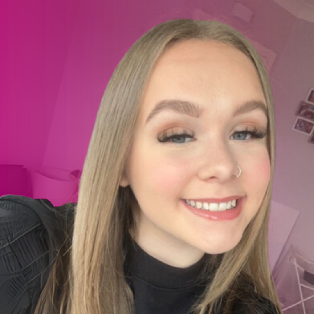 A woman with long hair is smiling at the camera, she is wearing a black top. There is a pink tint to the background. There is a link to a web page on this website.
