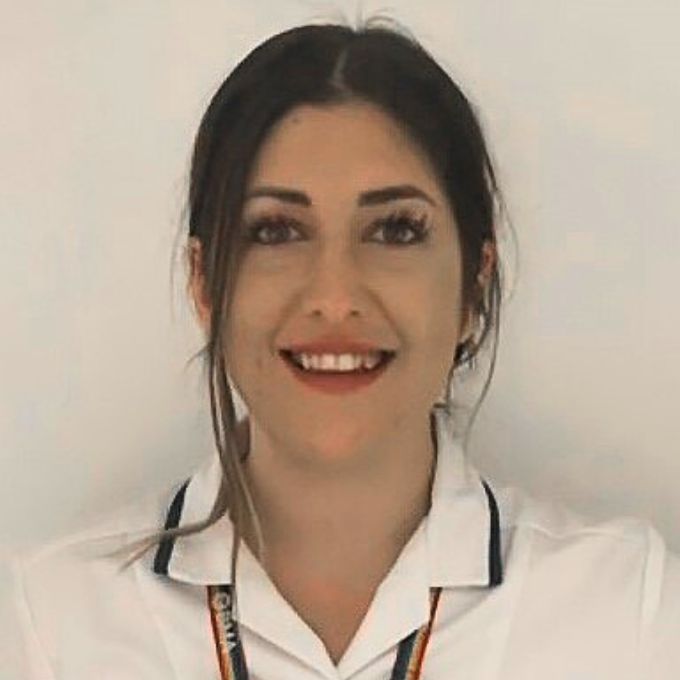 A person wearing a white shirt with dark trim on the collar and a lanyard around their neck.