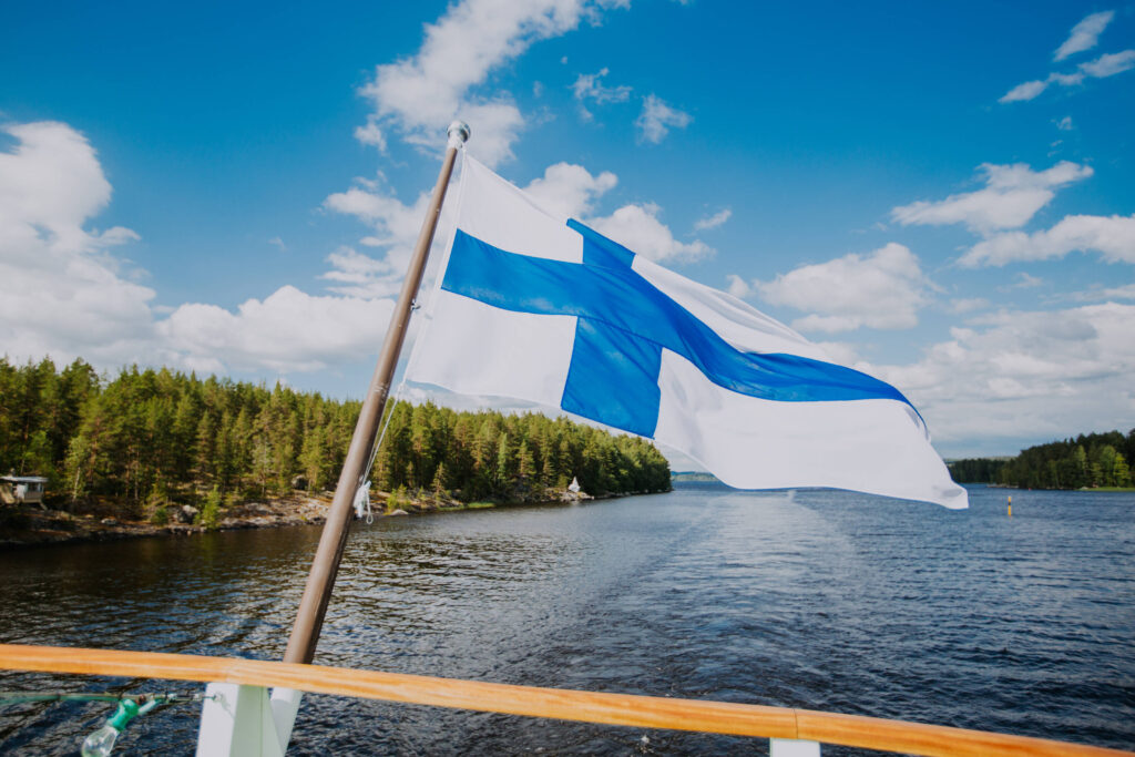 The Finnish flag on the back of a boat on a river in Finland.