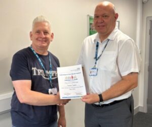 Two men proudly holding a certificate in a modern office setting.