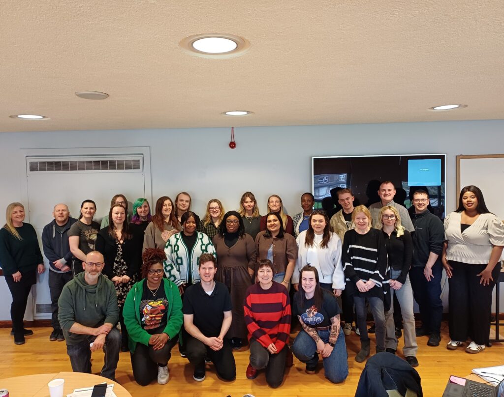 A group photograph in a large space, people are sitting and standing.