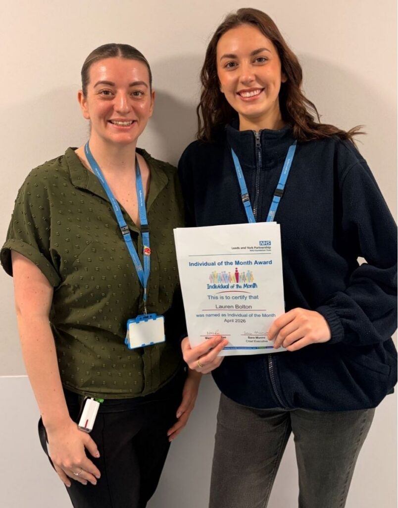 Two women smiling, one holding an Individual of the Month award certificate from the Leeds and York Partnership NHS Trust.