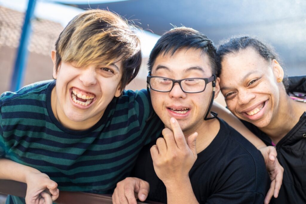 Three people with learning disabilities smiling. 