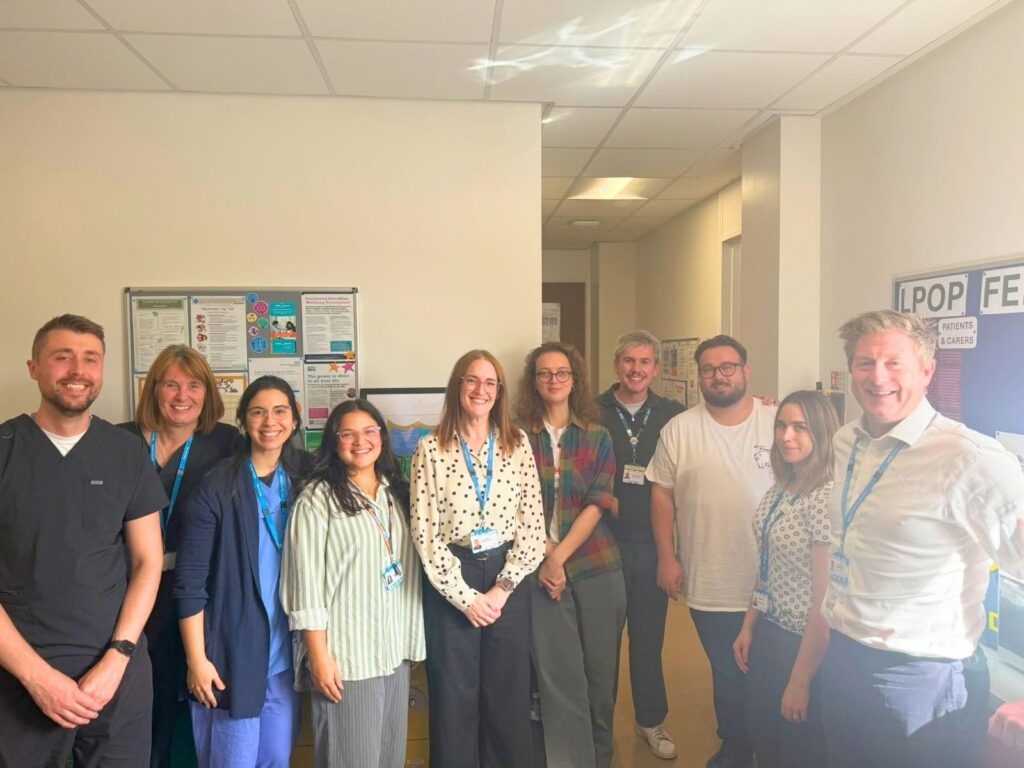 A group of smiling healthcare professionals standing together in an office corridor.